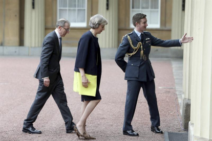 La conservadora, Theresa May (c), y su marido, Philip John (i), a su llegada al palacio de Buckingham para recibir el mandato de la reina Isabel II para formar gobierno.-EFE/Dominic Lipinski