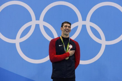 Phelps sonríe en el podio con el oro con el que recupera el título olímpico en los 200 mariposa.-ODD ANDERSEN / AFP