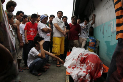 Un grupo de familiares permanece junto al cuerpo de un supuesto drogadicto asesinado durante una operación policial contra las drogas ilegales al interior de una mezquita en Manila.-FRANCIS R. MALASIG / EFE
