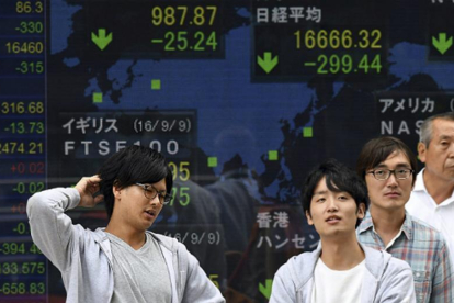 Japoneses en Tokio ante un monitor con la evolución de la bolsa.-FRANK ROBICHON