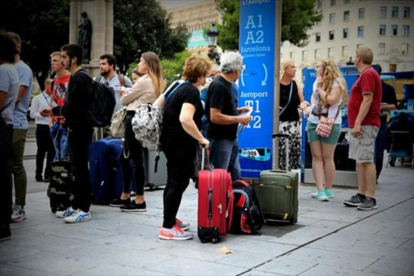 Varios turistas esperan el autobús al aeropuerto en la plaza de Catalunya.-FERRAN NADEU