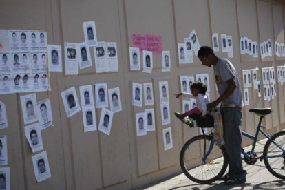 Una niña señala fotografías de los estudiantes desaparecidos, este jueves en un mural en Ciudad Juárez.-Foto: REUTERS / STRINGER
