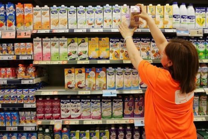 Una trabajadora ordena los productos en la estantería de un supermercado.-RICARD CUGAT
