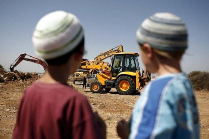 Dos niños judíos observan una retroexcavadora utilizada en la construcción de unas 50 viviendas en el asentamiento judío de Ariel .-EFE / OLIVIER WEIKEN