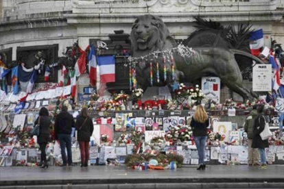 Homenajes a las víctimas en varios puntos de París. Sobre estas líneas, la placa conmemorativa en las antiguas oficinas de 'Charlie Hebdo'. A la derecha, un lector del último número de la revista en Niza.-REUTERS / CHARLES PLATIAU / ERIC GAILLARD / AP / CHRISTOPHE ENA / EFE / BENOIT TESSIER