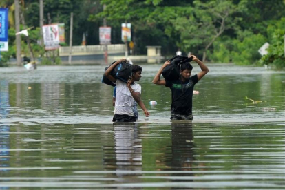 Dos jóvenes caminan entre las aguas a unos 17 kilómetros de la capital de Sri Lanka, Colombo.-ISHARA S KODIKARA