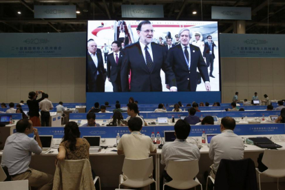 Los periodistas siguen desde la sala de prensa la llegada del presidente del Gobierno español en funciones, Mariano Rajoy (i), al aeropuerto Internacional de Hangzhou Xiaoshan, para participar en la cumbre del G20.-EFE / JUAN CARLOS HIDALGO