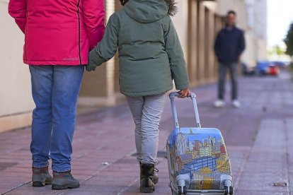 Una niña camina portando una maleta entre sus progenitores. --MIGUEL ÁNGEL SANTOS (PHOTOGENIC)