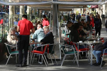 Varios camareros sirven a clientes en terrazas de bares del paseo de Gràcia.-/ DANNY CAMINAL