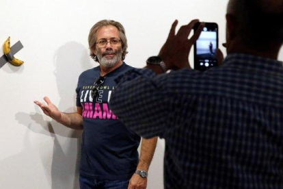 Un hombre se retrata junto a la obra del artista italiano Maurizio Cattelan.-RHONA WISE / EFE