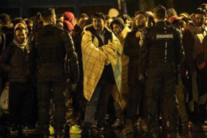 Un grupo de foráneos esperan un autobús para su traslado durante una operación de desalojo de campamentos de migrantes en París.-JULIEN DE ROSA (EFE)