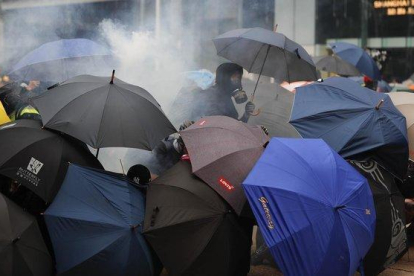 Varios manifestantes se protegen con paraguas de los gases lacrimógenos lanzados por la policía, este domingo en Hong Kong.-AP /  / VINCENT THIAN