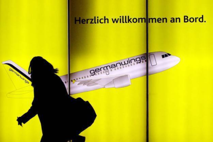 Una mujer pasea por delante de un cartel publicitario de Germanwings en el aeropuerto de Colonia, en Alemania.-Foto:   OLIVER STRATMANN / AFP