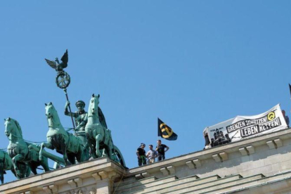Los ultras de Movimiento Identitario, en lo alto de la Puerta de Brademburgo.-EFE / PAUL ZINKEN