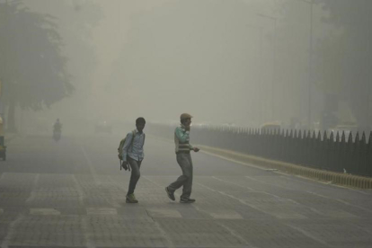 Peatones en medio de una intensa niebla toxica en Nueva Delhi.-AFP / SAJJAD HUSSAIN