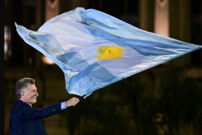 Macri ondea una bandera argentina en el mitin de clausura de su campaña electoral, en Córdoba.-AFP / RONALDO SCHEMIDT