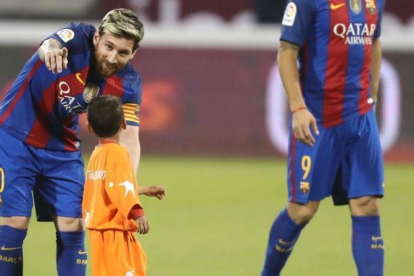 Messi indica a Murtaza, el niño afgano, que debe abandonar el césped en Doha.-AFP / KARIM JAAFAR