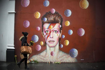 Flores ante un mural de David Bowie en la pared del comercio Morley, en Brixton (Londres), lugar de nacimiento del cantante.-