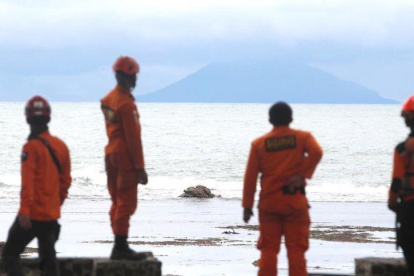 Miembros de los servicios de rescate observan la actividad del volcán Anak Krakatau desde la playa indonesia de Carita.-ADI WEDA (EFE)