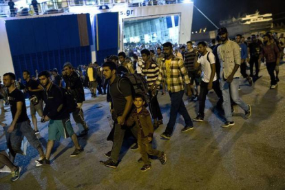 Cientos de inmigrantes desembarcan de un ferry en el puerto de El Pireo, cerca de Atenas, la noche del martes.-AFP / ANGELOS TZORTZINIS