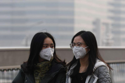 Dos chicas se protegen de la contaminación en Pekín el pasado lunes.-AFP / GREG BAKER