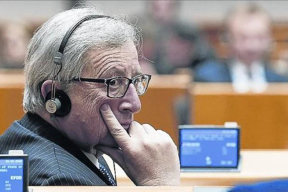 Jean-Claude Juncker, con unos auriculares de traducción en un pleno del Parlamento europeo.-JULIAN WARNAND