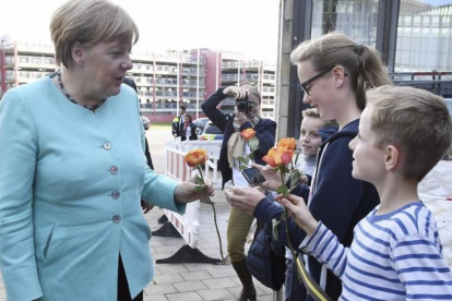 La cancillera Merkel, recibida con ramos de flores de niños a su llegada al Parlamento regional de Dusseldorf, con motivo del 70 aniversario de la CDU, el 30 de septiembre.-EFE / FEDERICO GAMBARINI