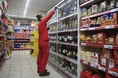 Una empleada repone los productos en un supermercado.-FERRAN NADEU