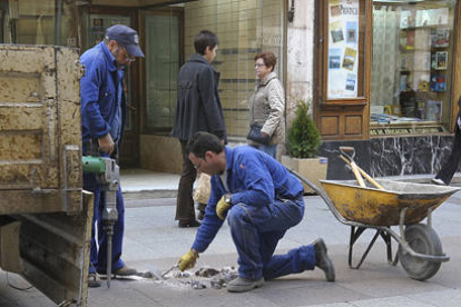 Trabajadores municipales trabajan en el Collado arreglando las baldosas que se rompen y para evitar los tropiezos de los peatones. / VALENTÍN GUISANDE-