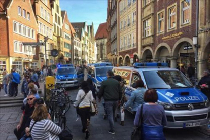 Vecinos y turistas circulan por el centro de Münster, entre furgonetas de la policía, tras el atropello de ayer.-/ AFP