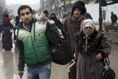 Una familia siria espera a ser evacuada de Alepo.-AFP