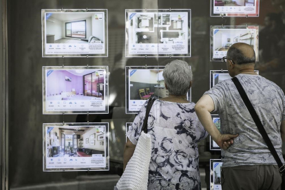Una pareja mira pisos de alquiler en una inmobiliaria de Barcelona.-JOAN CORTADELLAS