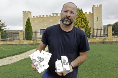 El encargado de la planta, Iván Rodríguez, posa frente al edificio en el que se encuentra el manantial con cajas de agua-LAT