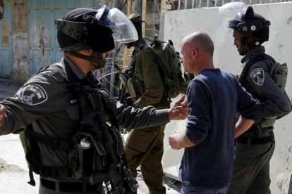 Soldados israelies arrestan a un joven palestino durante una protesta en la ciudad cisjordana de Hebron ayer lunes 17 de abril.-EFE / ABED AL HASHLAMOUN