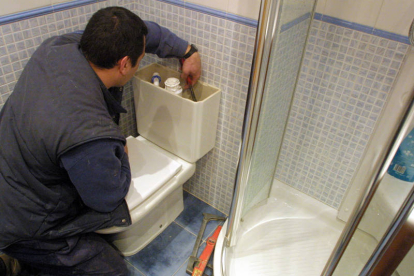 Un trabajador autónomo arregla la cisterna de un cuarto de baño en una vivienda de la capital soriana. / DS-