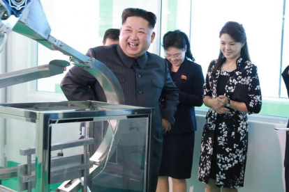 Kim Jong-un durante la visita a la fábrica, junto a su mujer, Ri Sol-ju (segunda por la derecha), en una foto difundida el domingo por la KCNA.-AFP