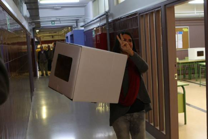Una voluntaria hace el signo de la victoria antes de abrir el punto de participación, en Girona.-