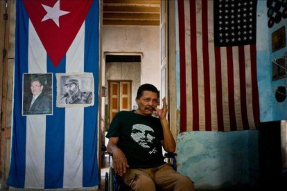 El cubano Armando Ricart Batista, actor y exboxeador, posa ante la bandera cubana y retratos de los Castro en su casa de la Habana.-RAMÓN ESPINOSA / AP