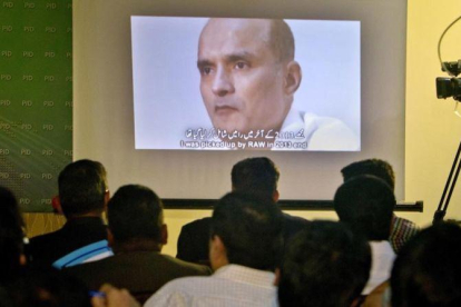 Unos periodistas observan la imagen de Jadhav mientras el portavoz del ejército paquistaní explcia su condena.-ANJUM NAVEED
