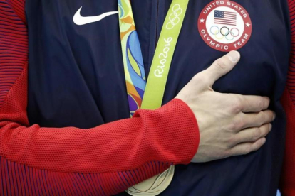 Michael Phelps se lleva la mano al pecho mientras suena el himno de EEUU, tras el triunfo en el relevo 4x100. La última de sus 28 medallas olímpicas.-AFP / ODD ANDERSEN