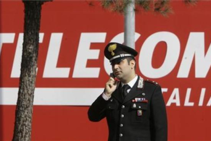 Un policía habla con su móvil frente a la sede de Telecom Italia en Rozzano-AP / LUCA BRUNO