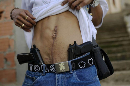 Un traficante de drogas muestra su herida de bala y su arma en Caracas.-Rodrigo Abd / AP