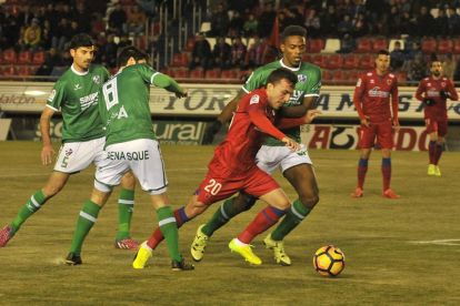 Pablo Valcarce conduce un balón ante varios jugadores del Huesca.-MARÍA FERRER