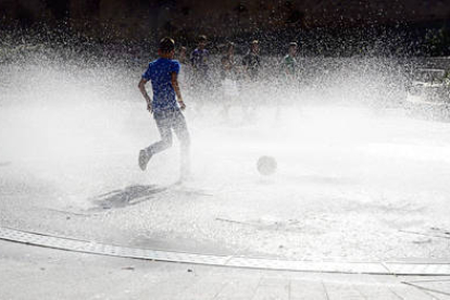 Un joven, dentro de la fuente del Rincón de Bécquer, se refresca gracias al agua que expulsa los surtidores. / A. M.-