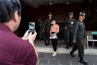 Una turista se fotografía con unos soldados en Bangkok, Tailandia.-AFP / LILLIAN SUWANRUMPHA