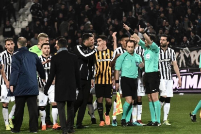 Árbitros y jugadores, durante los incidentes en el tramo final del partido en campo del PAOK.-/ AFP / SAKIS MITROLIDIS