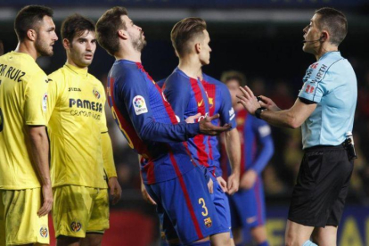 Piqué discute con el árbitro del encuentro entre el Villarreal y el Barcelona.-MIGUEL LORENZO