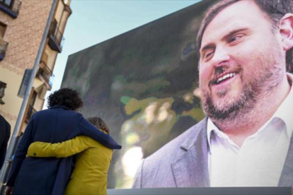 Marta Rovira se abraza a la también candidata Carme Forcadell bajo la mirada de Oriol Junqueras desde la pantalla, en el acto central en el Born.-JORDI COTRINA