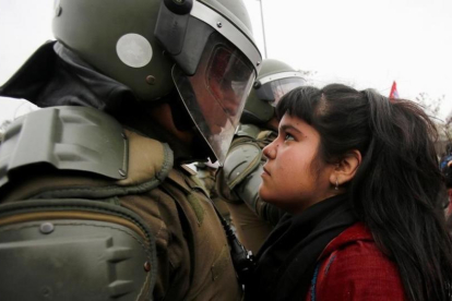 Una manifestante mira a un policía durante una marcha con motivo del 43 aniversario del golpe de Estado en Chile.-CARLOS VERA / REUTERS