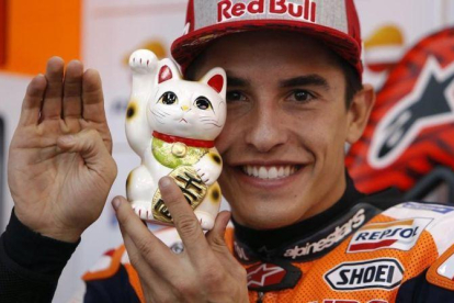 Marc Márquez muestra a su gato de la suerte japonés, al que tiene junto a él en el box del equipo Repsol Honda, en Motegi (Japón).-REPSOL MEDIA / JJAIME OLIVARES